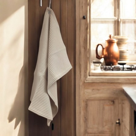 Torchon beige en nid d’abeille accroché dans une cuisine en bois lumineuse