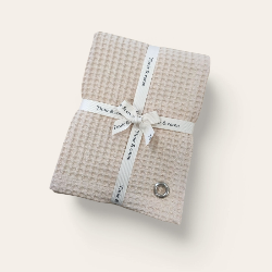 Torchon beige en nid d’abeille accroché dans une cuisine en bois lumineuse