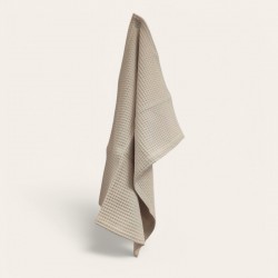 Torchon beige en nid d’abeille accroché dans une cuisine en bois lumineuse